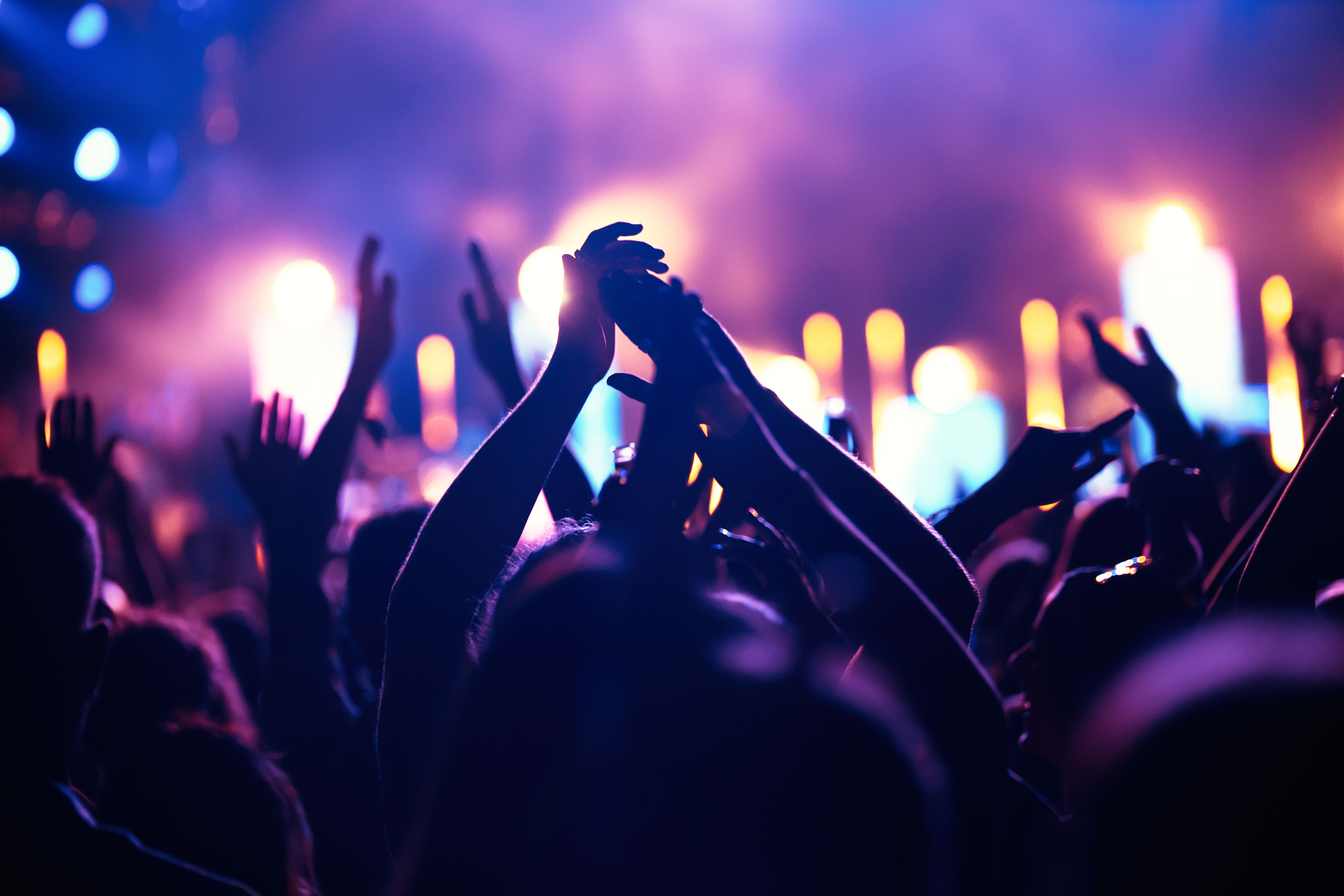 Happy cheering crowd with hands in air at music festival